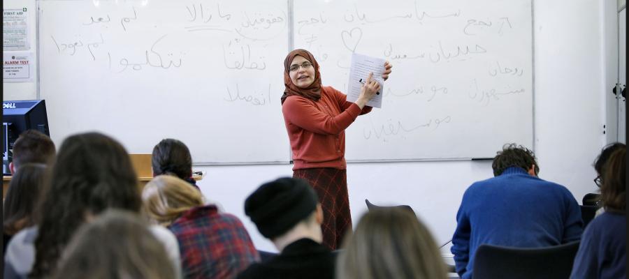 Teaching Fellow in Islamic and Middle Eastern Studies holding a document up in front of the students