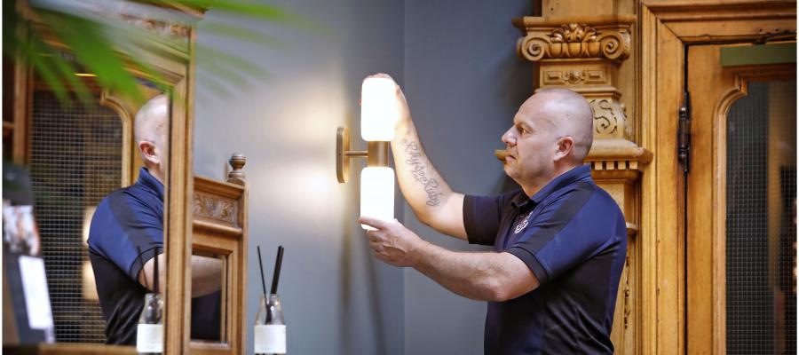 Member of staff checking a light fitting on a wall