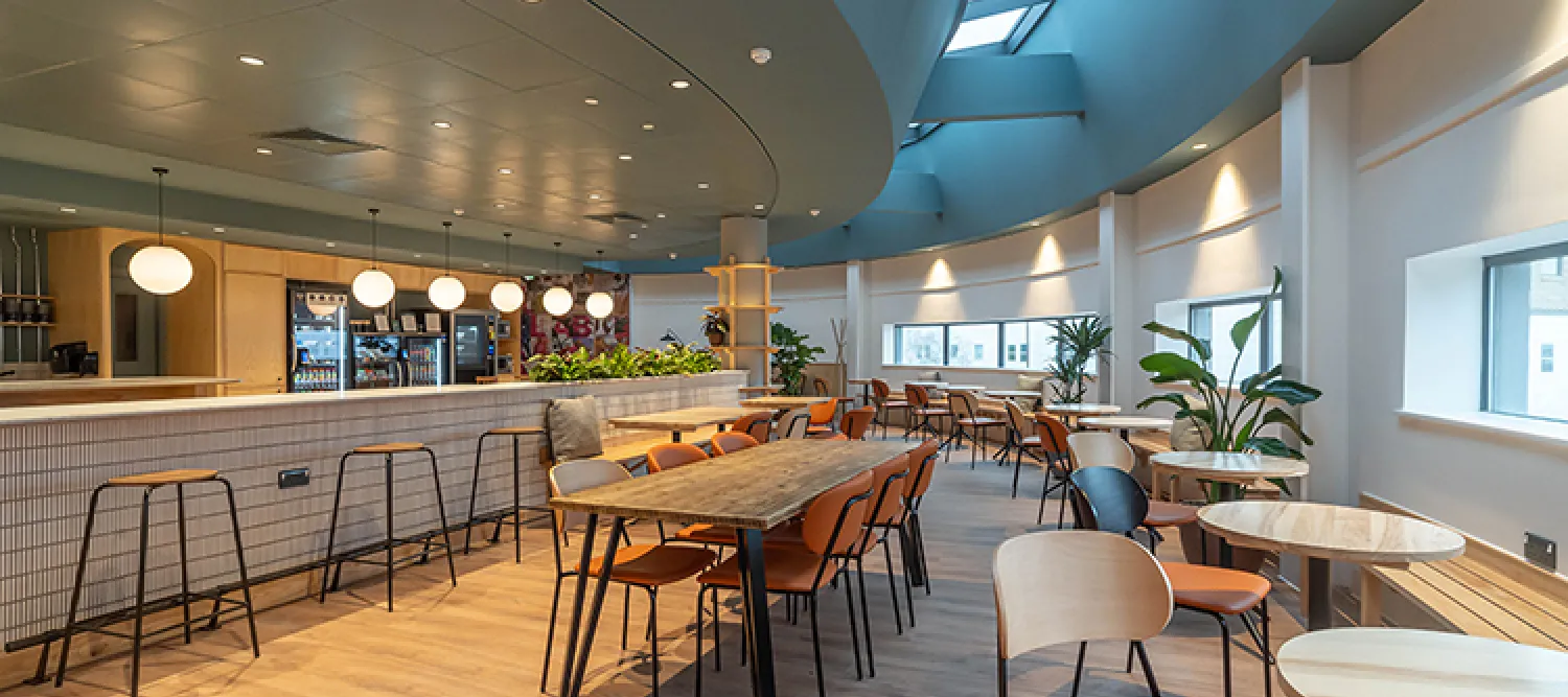 A curved room with tables and chairs and windows looking outside 