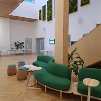 A room with green sofas and small stools