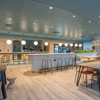 A room with a bar and bar stools, tables and chairs 