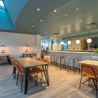 A room with a bar and bar stools, tables and chairs 