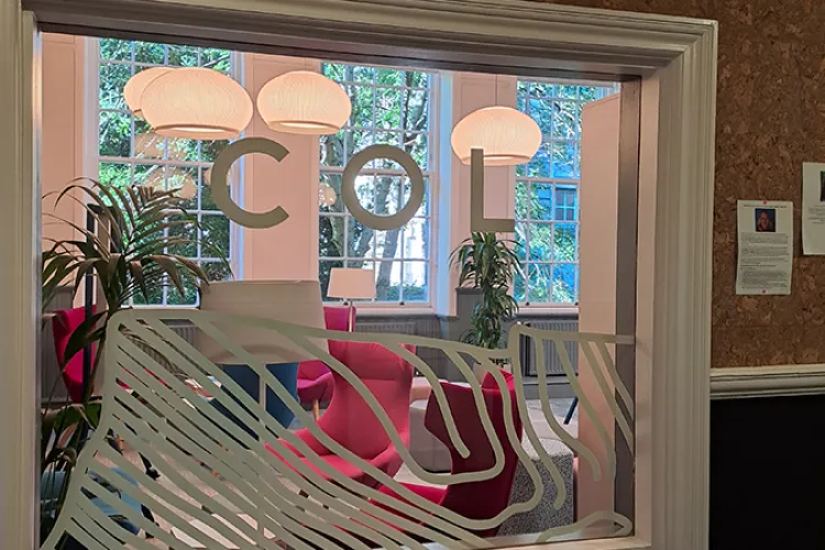 A window with a white frame with the letters COL on the glass in white 