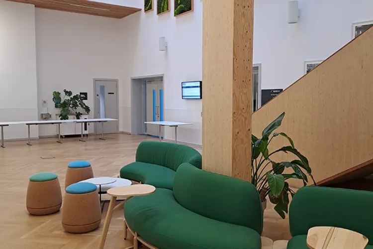 A room with green sofas and small stools
