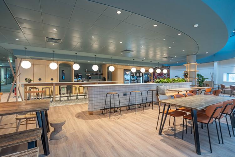 A room with a bar and bar stools, tables and chairs 