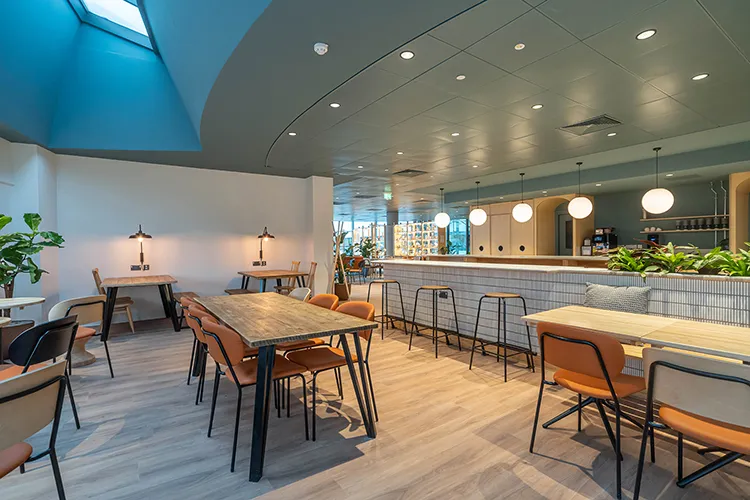 A room with a bar and bar stools, tables and chairs 