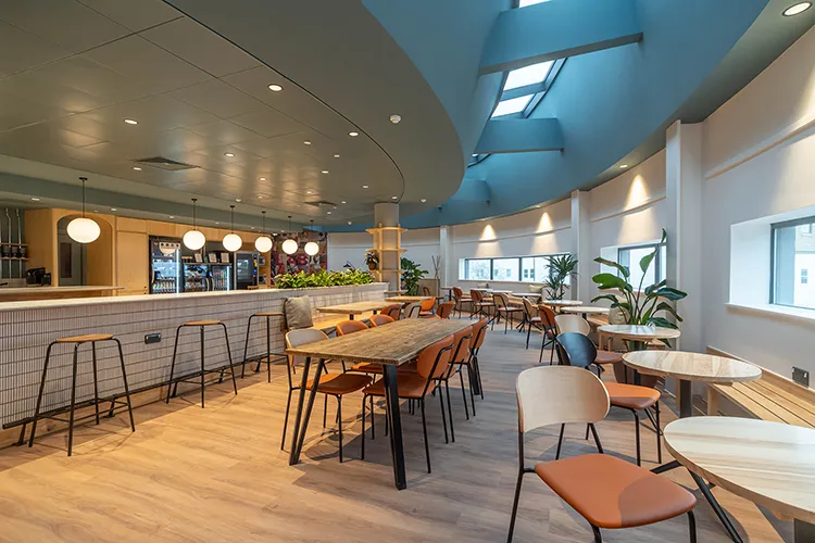 A curved room with tables and chairs and windows looking outside 