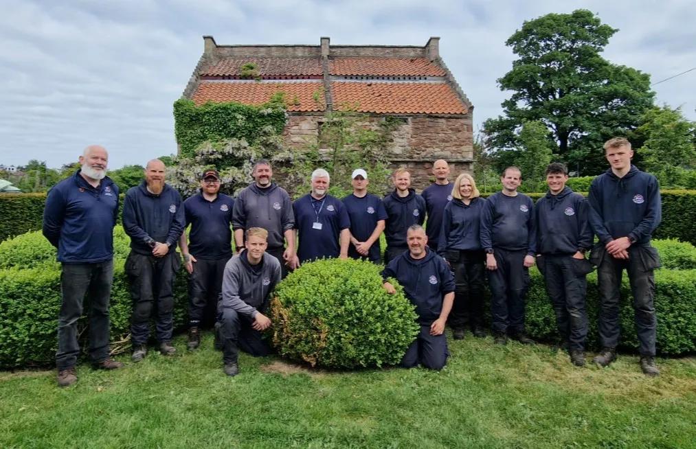 Fourteen people standing in a garden